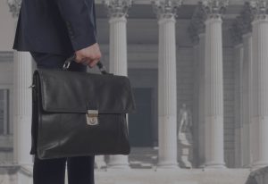 A man holding a briefcase in front of pillars.