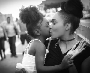 A woman kissing a young girl on the cheek.