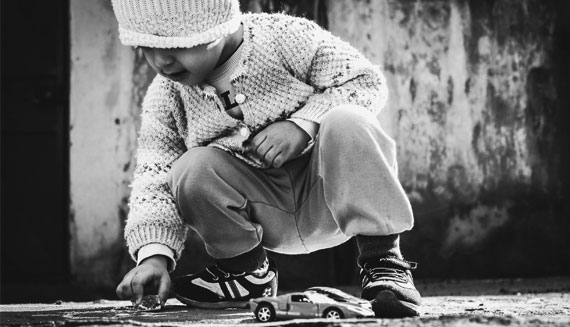 A young boy playing with toy cars outside.