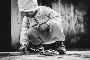 A young boy playing with toy cars on the ground.