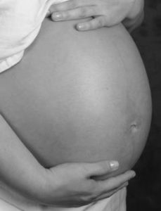 A pregnant woman is holding her belly.